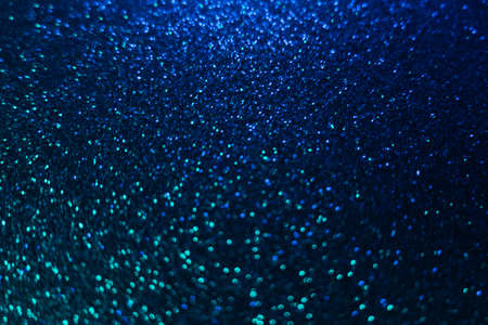 Color bokeh glow. Glitter background. Wet asphalt reflection. Defocused neon blue green light shiny...