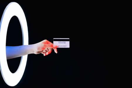 Bank technology. Digital payment. Global financial transaction. Female hand showing credit card CVV number in LED light circle isolated on dark black empty space background.の写真素材