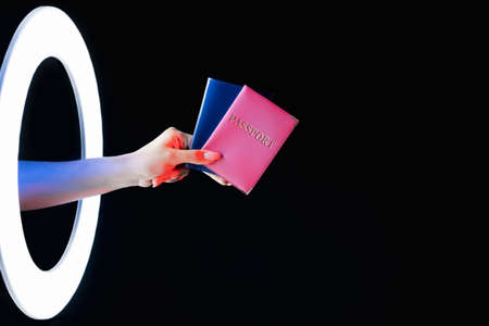 Passport control. Visa service. Foreign embassy. Female hand holding two citizenship ID in pink blue...