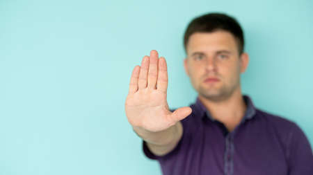 Stop gesture. Confident man. Closed way. Serious defocused guy in t-shirt holding forbidden hand up...
