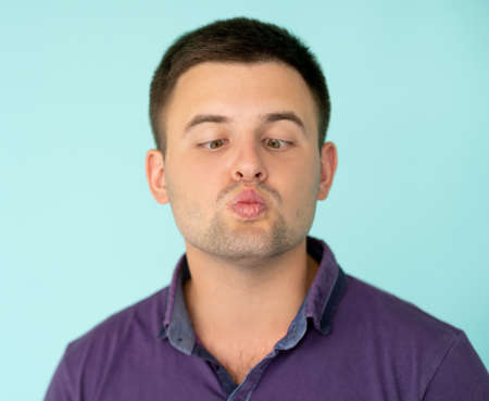 Silly man. Ridiculous face. Playing fool. Clueless guy in t-shirt shifting eyes to nose looking squint pouting lips isolated blue.の写真素材