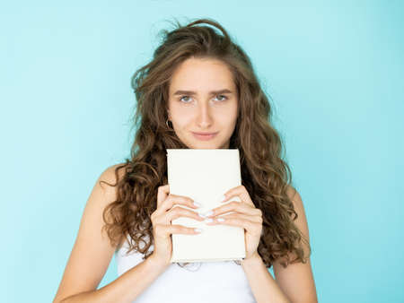 Lovely literature. Pretty woman. Enjoying reading. Cute smiling curly lady holding book in head...