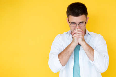 Considering idea. Hopeful man. Faithful believes. Handsome concentrated guy holding hands front of...