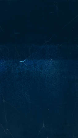 Scratched filmstrip. Aged texture. Flecks glow on dark background.の写真素材