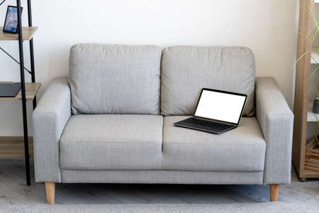 Computer mockup. Online technology. Digital life. Opened laptop with blank screen laying on sofa...