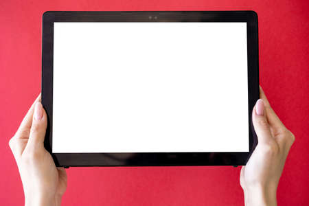 Computer mockup. Online education. Digital technology. Unrecognizable woman holding tablet computer in hands with blank screen isolated red.の写真素材