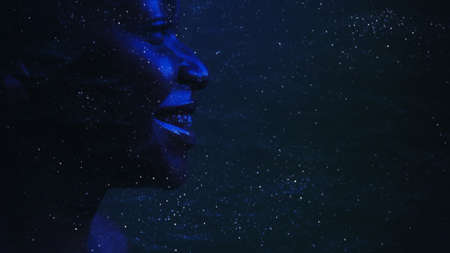 Galaxy inspiration. Astrology science. Neon blue side view silhouette of smiling woman face on dark cosmic dust star night sky empty space background.の写真素材
