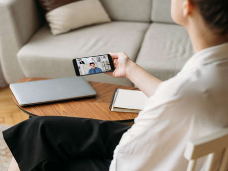 Virtual conference. Working from home. Mobile video chat. Relaxed female employee using phone...