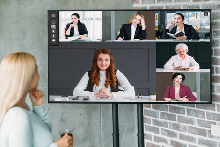 Video briefing. TV conference. Corporate telecommuting. Female business team discussing strategy plan working online in digital office on screen.の写真素材
