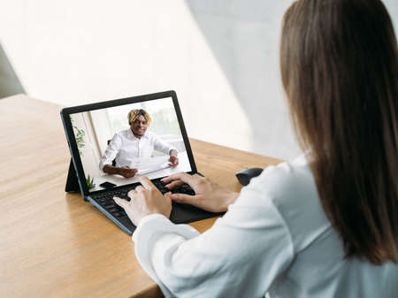 Video call. Remote work. Digital meeting. Business woman using laptop discussing project online with male partner on screen in virtual home office.の写真素材