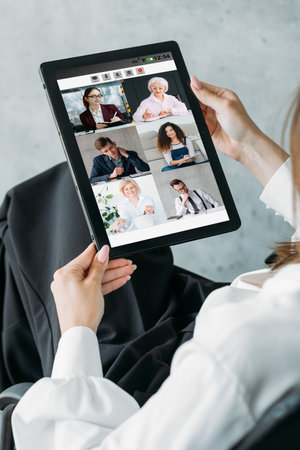 Work video chat. Digital interview. Online business management. Female executive discussing project with team on tablet screen in virtual office.の写真素材