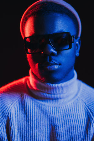 Neon light man. Night portrait. Cyberpunk fashion. Cool handsome guy face in sunglasses in bright...