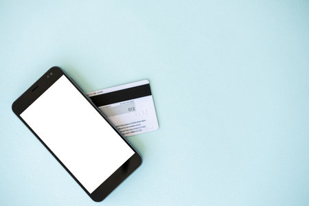 Bank payments. Mobile mockup. Online technology. Smartphone with white blank screen and plastic credit card isolated blue copy space.の写真素材