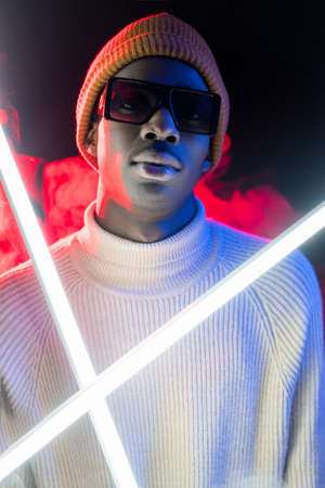 Urban fashion. Neon hipster. Youth nightlife. Street wear. Stylish young confident man in casual outfit in glowing vibrant light at night.の写真素材