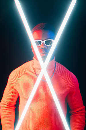 Male power. Neon light people. Cyberpunk sci fi. Confident serious man night portrait with bright LED crossed lamps on dark studio background.の写真素材
