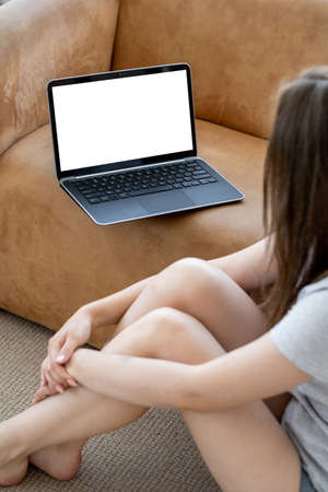 Home rest. Casual woman. Computer mockup. Relaxed unrecognizable lady looking laptop with blank screen sitting floor in light room interior.の写真素材