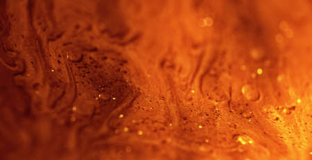 Glitter paint flow. Molten gold texture. Floating ink. Defocused yellow orange sparkling fluid...