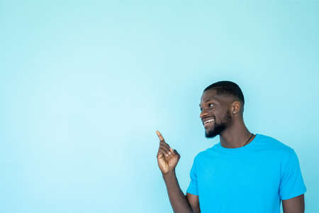 Pointing man. Promotion banner. Content advertising. Discount offer. Happy guy demonstrating blue empty space recommendation background.の写真素材