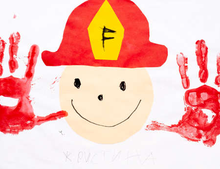 Kids art. Happy fireman. Creative improvisation. Artistic work of smiling face collage in professional firefighter cap and hand palms print red color.の写真素材