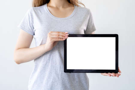 Computer mockup. Online education. Internet technology. Unrecognizable woman holding tablet computer in hands with blank screen isolated white.の写真素材