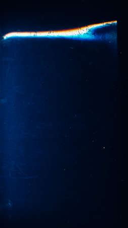 Grunge overlay. Dust scratches texture. Old film effect photo editor layer. Blue stain dirt defect rainbow color glow on dark aged empty space illustration abstract background.の写真素材