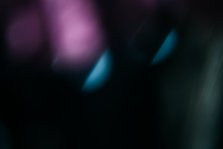 Blur light leak. Lens flare. Bokeh rays. Defocused purple blue color flecks glow on dark night black abstract copy space background.の写真素材