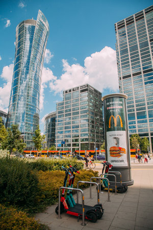 Warsaw, Poland - June 27, 2022: Business architecture. Downtown industry. City center. Modern glassy buildings and street advertising parking electric scooter daylight.のeditorial素材