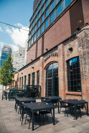 Warsaw, Poland - June 22, 2022: Food court zone. Creative landmark. Historical architecture. Modernized old building with empty cafe tables in sunlight day.のeditorial素材