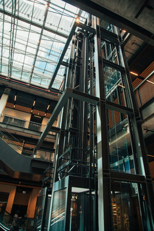 Warsaw, Poland - June 22, 2022: Shopping center. Grunge architecture. Industrial city. Modern building with high double ceiling window roof glassy elevator in sunlight day.のeditorial素材