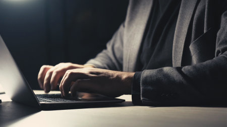 Vertical video. Hard work. Busy man. Overwork schedule. Unrecognizable business male typing laptop in dark room interior.の写真素材