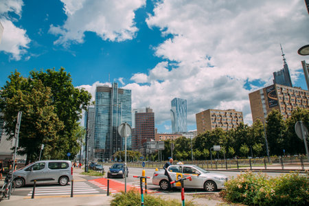 Warsaw, Poland - June 27, 2022: Cityscape view. City architecture. Central district. Street with diverse buildings parking cars walking people in sunny daylight.のeditorial素材