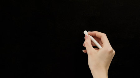Chalk writing. Back to school. Learning education. Female teacher hand at blank clean blackboard...
