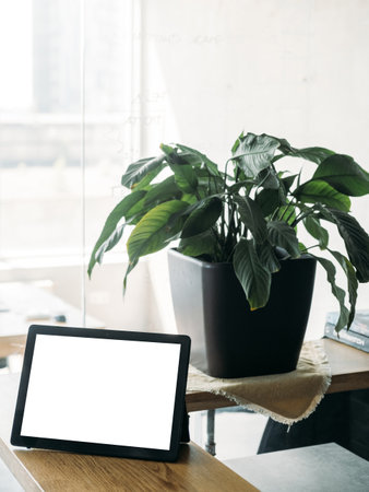 Virtual connection. Digital mockup. Online technology. Tablet computer with blank screen on desk in light room interior.の写真素材