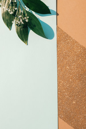Floral layout. Greeting card. Spring decoration. Green leaf flowers white blank mockup paper composition on golden beige glitter empty space background.の写真素材