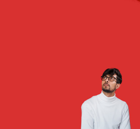 Curious face. Advertising background. Special offer. Portrait of confused pensive smart man reading invisible information on red color empty space background.の写真素材