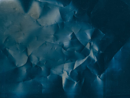 Crinkled texture. Aged film overlay. Distressed foil. Blue color flare dust scratches noise on dark wrinkled weathered abstract illustration background.の写真素材
