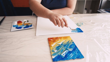 Artwork creation. Female artist. Abstract picture. Unrecognizable woman painting on canvas with spatula and paint.の写真素材