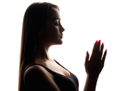 Prayer silhouette. Faith forgiveness. Repentance salvation. Dark backlit profile of religious woman with folded hands on white free space background.の写真素材