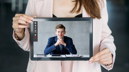 Video coaching. Online expert. Internet conference. Woman showing confident business man working at digital office on tablet screen.の写真素材