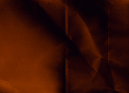 Creased paper. Distressed texture. Grunge overlay. Orange black crinkled noise on dark uneven...