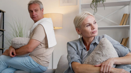 Family quarrel. Offended couple. Disagreement problem. Angry middle-aged man and woman sitting sofa...