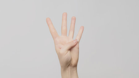 Hand gesture. Four number. Woman showing trio fingers up on light gray background.の写真素材