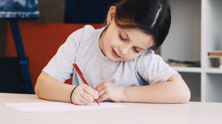 Kids painting. Art hobby. Creative time. Happy girl drawing with pencil on paper sitting table in...