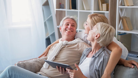 Family rest. Happy meeting. Enjoying moment. Smiling mother father and daughter talking together communicating in light home interior.の写真素材