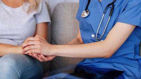 Doctor support medical care. Unrecognizable woman nurse with stethoscope holding patients hands encouraging sick female indoors.の写真素材