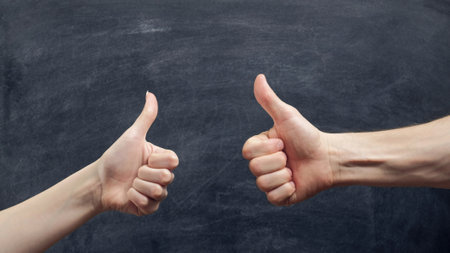 Like gesture. Approval sign. Man and woman hands showing thumb up on chalkboard background.の写真素材