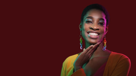 Glowing smile. Dental care. Oral beauty. Confident cheerful woman face with perfect healthy white teeth in neon light on dark red empty space background.の写真素材