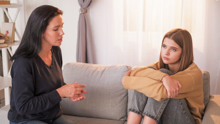Domestic blaming. Upbringing problem. Criticizing mother talking with teenage daughter about life and responsibility sitting light home interior.の写真素材