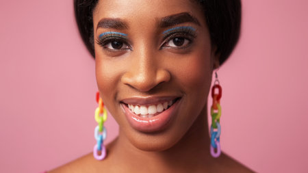 Color makeup. Happy face. Summer beauty. Cheerful smiling woman with full lips blue eye shadow long eyelashes rainbow earrings on pink free space.の写真素材