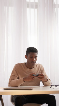 Gadget leisure. Mobile game. Watch video. Work break. Young focused man sitting at table with...